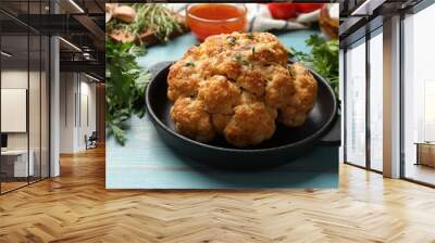 Delicious baked cauliflower in baking dish on light blue wooden table, closeup Wall mural