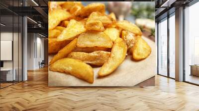 Delicious baked potato wedges on parchment paper, closeup Wall mural