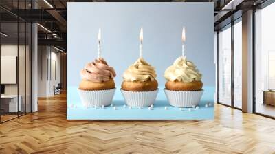 Delicious birthday cupcakes with candles on light background Wall mural