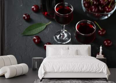 Delicious cherry liqueur in glasses and berries on black table, closeup Wall mural