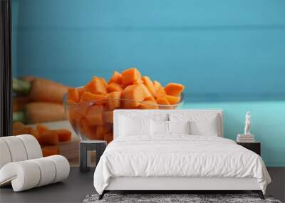 Delicious chopped carrot in bowl on light blue wooden table, space for text Wall mural