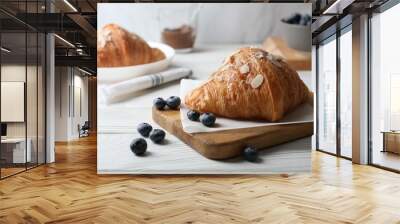 Delicious croissant with almond flakes and blueberries on white wooden table, closeup Wall mural