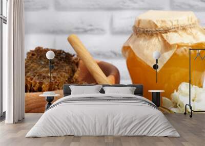 Delicious honey, combs and different flowers on wooden table near white brick wall Wall mural