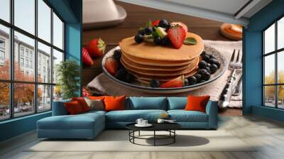 Delicious pancakes with fresh berries and butter served on wooden table, closeup Wall mural