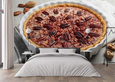 Delicious pecan pie in baking dish and fresh nuts on gray textured table, closeup Wall mural