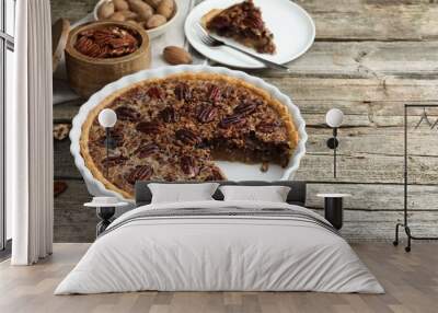 Delicious pecan pie in baking dish and fresh nuts on wooden table. Space for text Wall mural