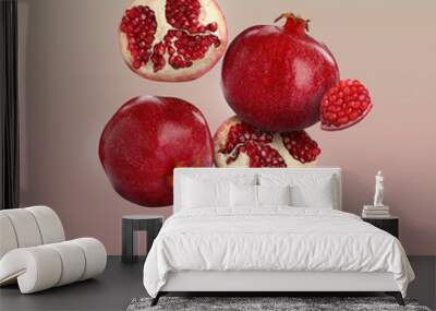 Delicious ripe pomegranate fruits falling on color background Wall mural