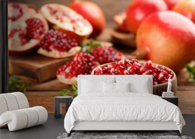 Delicious ripe pomegranate kernels in bowl on wooden table Wall mural