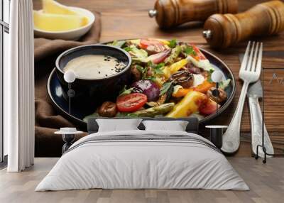 Delicious salad with grilled vegetables and sauce served on wooden table, closeup Wall mural