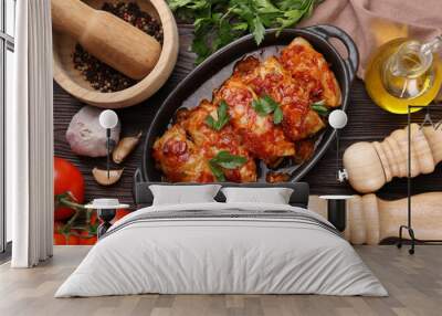 Delicious stuffed cabbage rolls cooked with tomato sauce and ingredients on wooden table, flat lay Wall mural