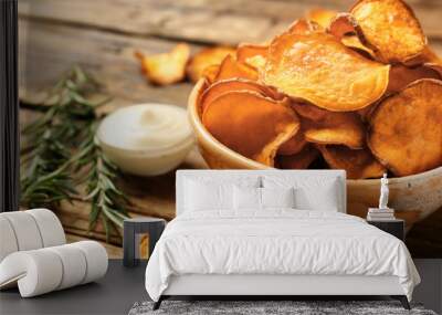 Delicious sweet potato chips in bowl, rosemary and sauce on table. Space for text Wall mural