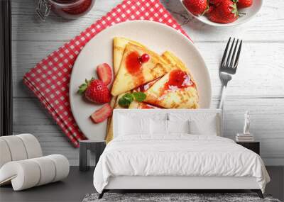 Delicious thin pancakes with strawberries and jam on white wooden table, flat lay Wall mural