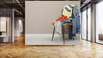 Different clothes on chair near light grey wall, space for text Wall mural