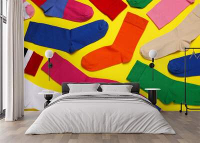 Different colorful socks on yellow background, flat lay Wall mural