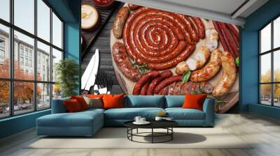 Different delicious sausages with herbs and sauces on black wooden table, flat lay. Assortment of beer snacks Wall mural