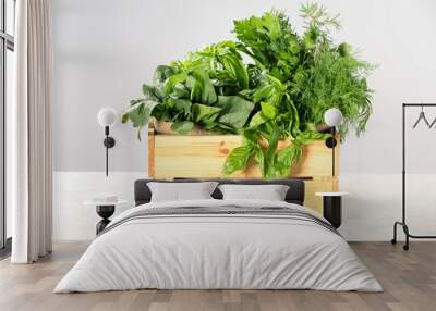 Different fresh herbs in wooden basket on white table Wall mural