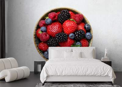 Different fresh ripe berries in bowl on light grey table, top view Wall mural