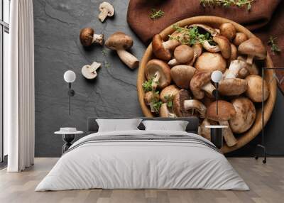 Different fresh wild mushrooms in bowl on black background, flat lay Wall mural