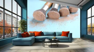 Different makeup brushes with crushed cosmetic product on light blue background, closeup Wall mural