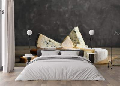 Different sorts of cheese and fork on wooden table against grey background Wall mural