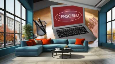 Display with censorship sign. Man using laptop at wooden table, closeup Wall mural