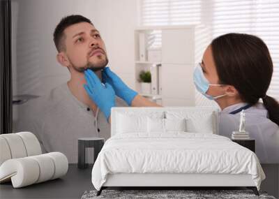 Doctor examining thyroid gland of patient in hospital Wall mural