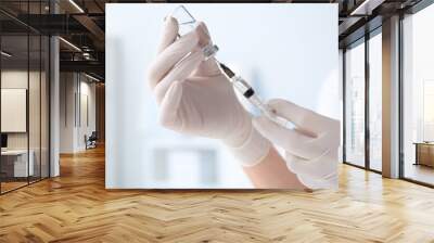 Doctor filling syringe with medication from vial on blurred background, closeup Wall mural