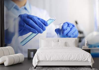 Doctor pouring blue liquid into flask, closeup. Laboratory analysis Wall mural