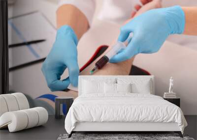 Doctor taking blood sample from patient with syringe at white table in hospital, closeup Wall mural