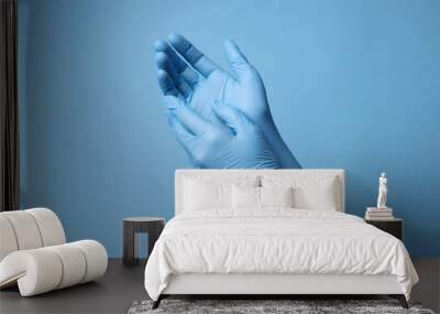 Doctor wearing medical gloves on light blue background, closeup Wall mural