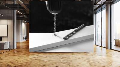 Drilling hole in plank on white table against black background, closeup Wall mural