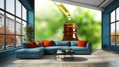 Dripping natural tea tree essential oil into bottle on blurred background, closeup Wall mural