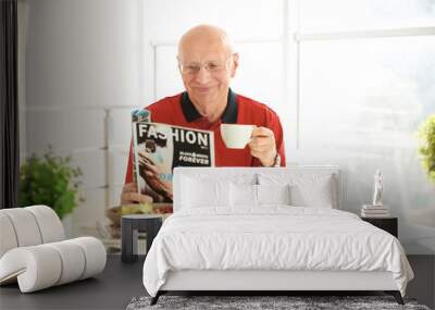 Elderly man reading magazine while having breakfast at home Wall mural