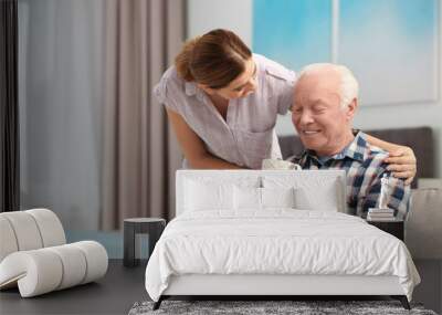 Elderly man with cup of tea near female caregiver at home. Space for text Wall mural