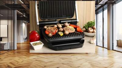 Electric grill with homemade sausages, vegetables and spices on wooden table Wall mural