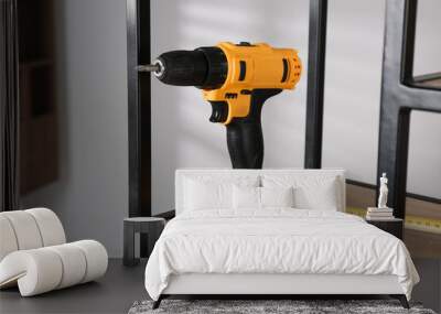 Electric screwdriver, pencils and tape measure on shelving unit indoors Wall mural