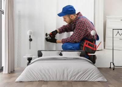 Electrician with pliers repairing power socket in room Wall mural