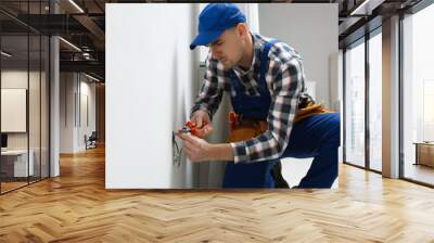 Electrician with pliers repairing power socket indoors Wall mural