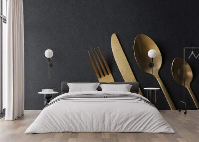 Elegant golden cutlery on black background, flat lay. Space for text Wall mural