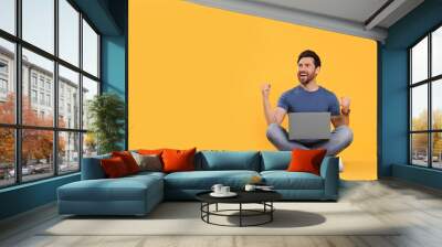 Emotional man with laptop on yellow background. Space for text Wall mural