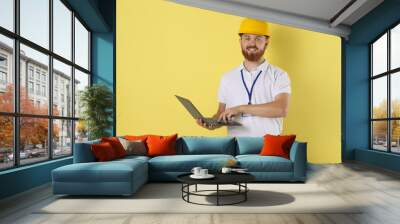 Engineer in hard hat with laptop on yellow background, space for text Wall mural