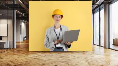 Engineer in hard hat with laptop on yellow background Wall mural