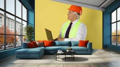 Engineer in hard hat with laptop on yellow background Wall mural