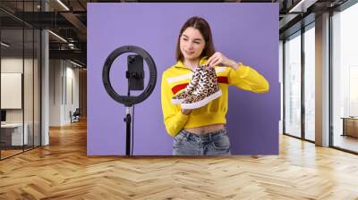 Fashion blogger reviewing sneakers and recording video with smartphone and ring lamp on purple background Wall mural