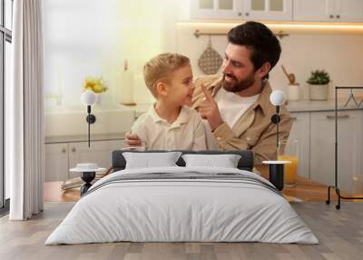 Father and his cute little son having breakfast at table in kitchen on sunny morning Wall mural