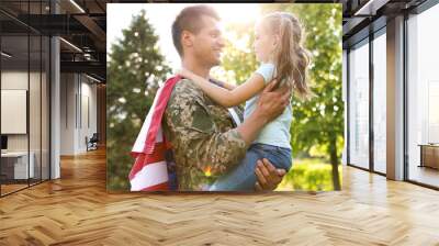 Father in military uniform with American flag holding his little daughter at green park Wall mural