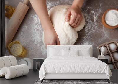 Female baker preparing bread dough at kitchen table, top view Wall mural