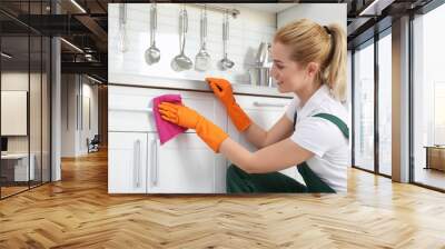 Female janitor cleaning cabinet with rag in kitchen Wall mural