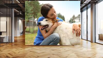 Female volunteer with homeless dog at animal shelter outdoors Wall mural