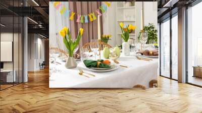 Festive Easter table setting with painted eggs, burning candles and yellow tulips in room Wall mural